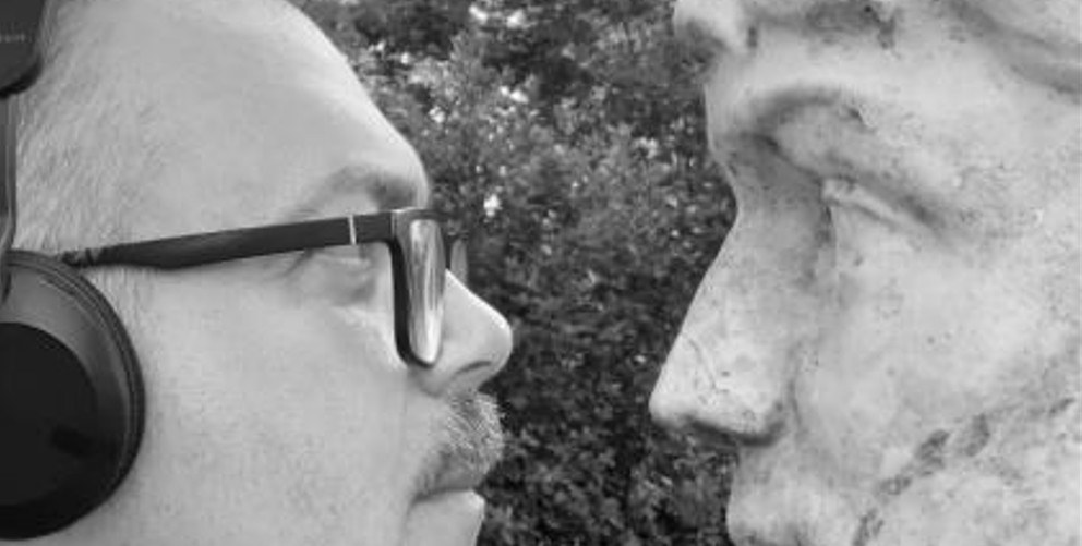 un uomo con le cuffie e una statua si guardano negli occhi