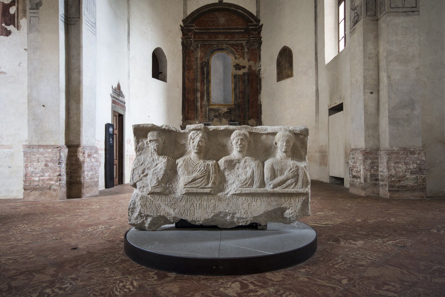 Cappella Meli con in primo piano una stele con raffigurate 4 persone